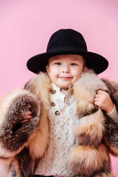 可爱的小男孩摆姿势在超大豪华皮草大衣和古典的帽子图片下载