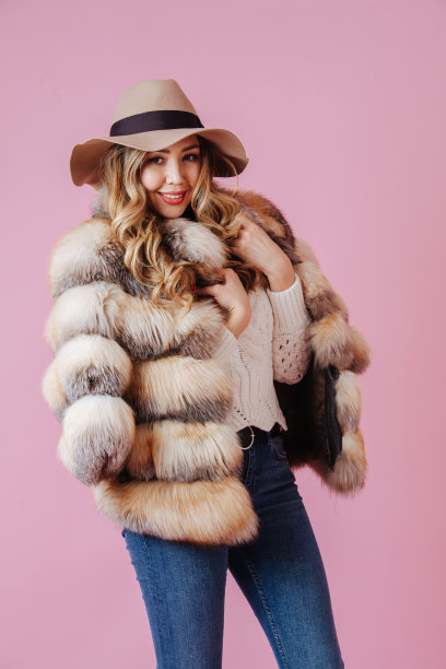 可爱迷人的女人，肩上披着华贵的裘皮大衣，头上戴着极线帽图片下载