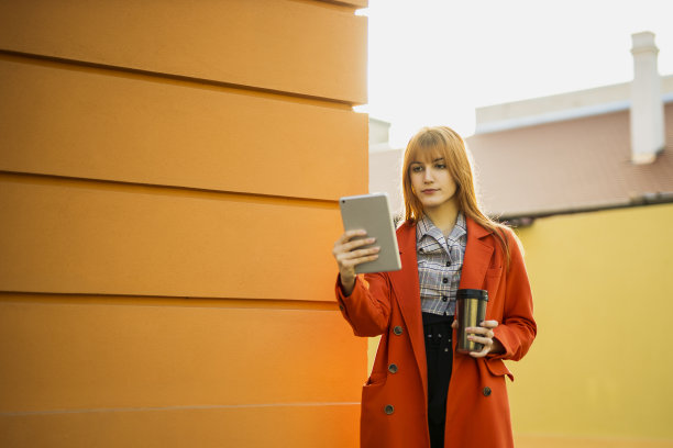 年轻的女商人喝着咖啡，在平板电脑上看杂志图片下载