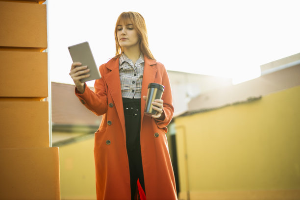 年轻的女商人喝着咖啡，在平板电脑上看杂志图片下载