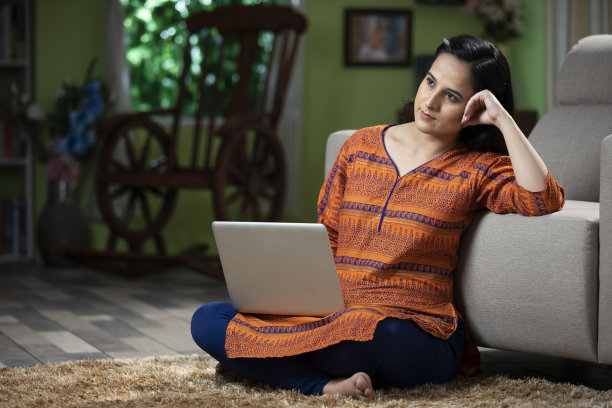 一个年轻女人坐在地板上使用笔记本电脑的肖像:库存照片图片下载