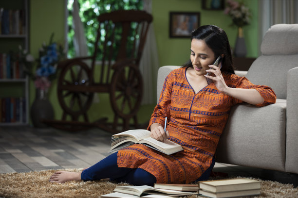 一个年轻女子坐在地板上用手机聊天的肖像:-库存照片图片下载