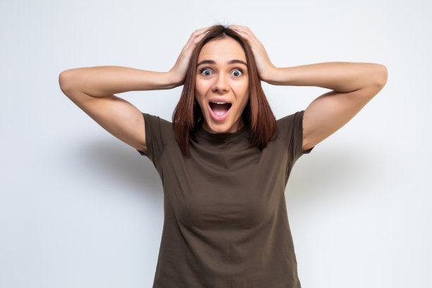 肖像迷人的惊讶兴奋害怕尖叫的青少年，手放在头上，张开嘴与棕色的长发，孤立在白色的背景图片下载