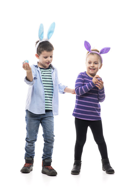 可爱好玩的小男孩和蹒跚学步的女孩用复活节兔子耳朵玩打蛋游戏。图片下载