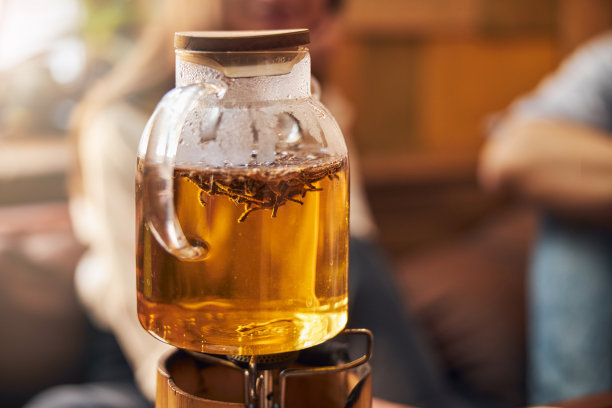 装有凉茶的玻璃茶壶，放在便携式煤气炉上图片下载