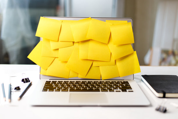 笔记本电脑屏幕上覆盖着黄色的不干胶便条。图片下载