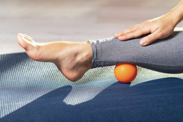 在家里的体操垫上用按摩球放松腿部肌肉的筋膜。防止腿部疲劳图片下载