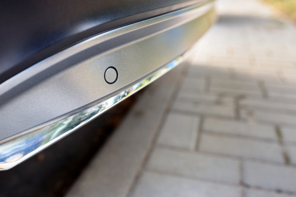 选择性聚焦后保险杠左侧停车传感器在豪华汽车保险杠后面近距离的光模糊与太阳耀斑背景与copyspace。图片下载