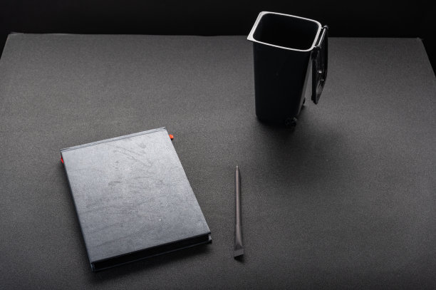 黑色的桌子上放着黑色的笔记本。笔记本和垃圾桶。垃圾桶在桌子上。黑暗的模型。图片下载