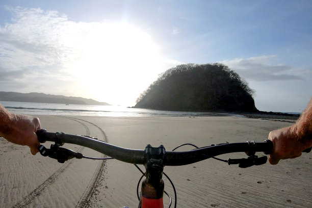 清晨，一名男子骑着山地车沿着沙滩而下图片下载