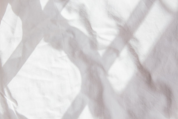 皱巴巴的白色床单，伴随着早晨从窗户透进来的光影。一夜之后，一张被拉直的床的皱巴巴的背景。白色背景图片下载