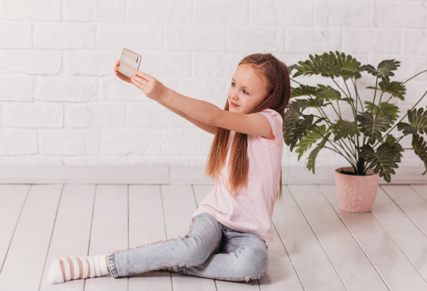 可爱的小女孩拿着智能手机拍照图片下载