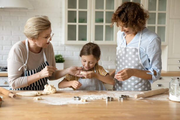 快乐的奶奶妈妈给小女孩讲解如何切饼干图片下载