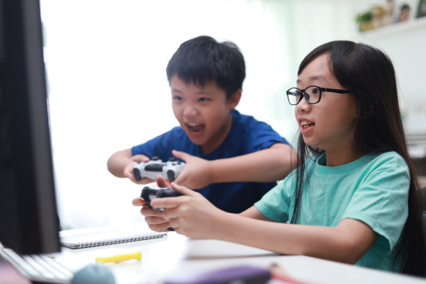 快乐的兄弟姐妹在客厅玩电子游戏。图片下载