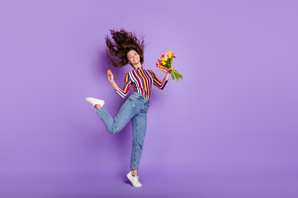 全身大小的女人跳优雅的照片保持鲜花微笑孤立生动的紫色背景图片下载