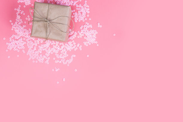 礼盒与棕色牛皮纸周围的粉红色雏菊和扁平的粉红色背景，春天，母亲节快乐，情人节和其他假日概念俯视图，现代设计图片下载