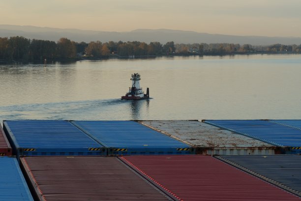 在俄勒冈州波特兰市的哥伦比亚河上，推式拖船在装载集装箱的船只附近航行。图片下载