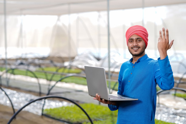 年轻的印度农民在温室或poly房子里使用笔记本电脑图片下载