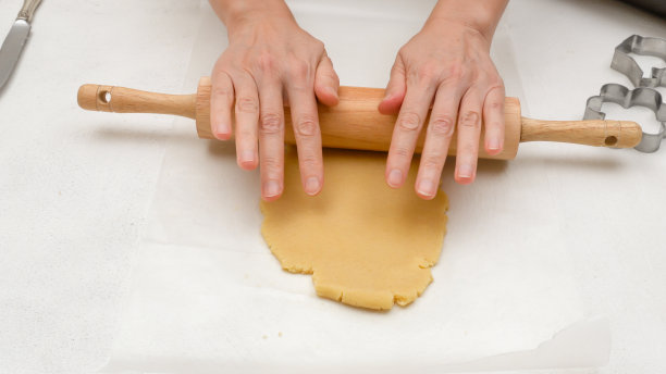 女人用手在厨房的桌子上擀面团。酥饼曲奇食谱，一步一步烘焙的过程图片下载