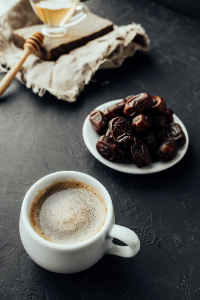 东方风格咖啡:新鲜的咖啡，泡沫，干枣，蜂蜜。黑暗的情绪图片。食物内容。垂直,有选择性的重点图片下载