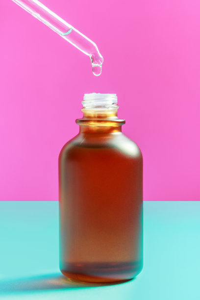 瓶与血清和移液管在蓝色和粉红色的背景特写。图片下载