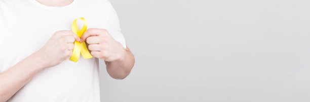 年轻男子身穿白色t恤，手持黄色丝带，象征自杀，骨癌，膀胱癌，肝癌和儿童癌症的概念。卫生保健。Copyspace。图片下载