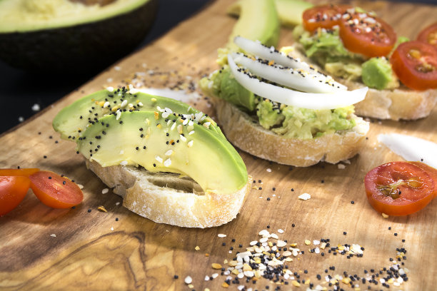 健康的牛油果吐司，带有种子和西红柿的开胃菜放在木板上，深色的背景。鳄梨三明治。食物照片，健康食物。图片下载