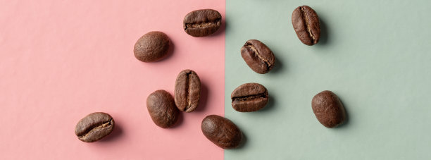 粉绿色硬纸板背景上的咖啡粒。图片下载
