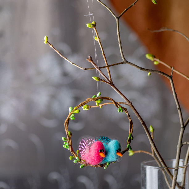 在室内装饰春天的树枝和花束时，用鸟做成的复活节花环图片下载