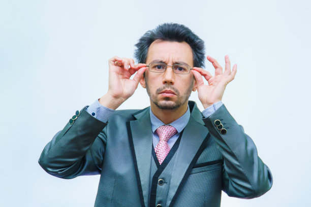 一个头发散乱穿着西装的男人正整理着他的眼镜图片下载