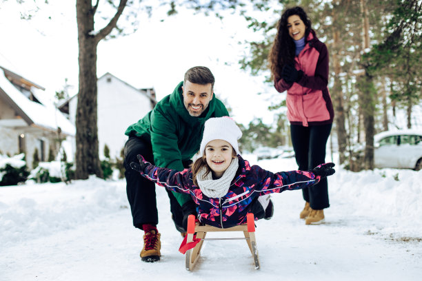 一个和爸爸妈妈玩雪橇的女孩的肖像图片下载