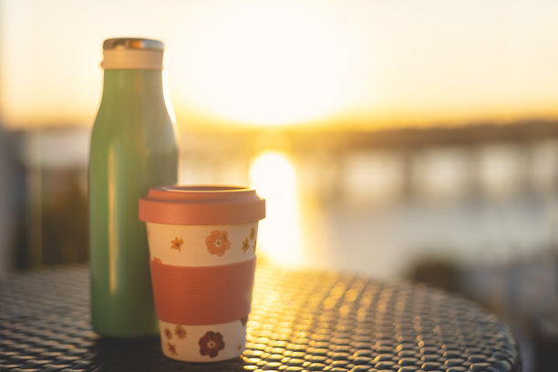 金属可重复使用的水瓶和竹可重复使用的杯子在阳光下。图片下载