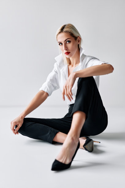时尚肖像性感时髦的女人摆姿势坐在地板上的白色工作室背景图片下载