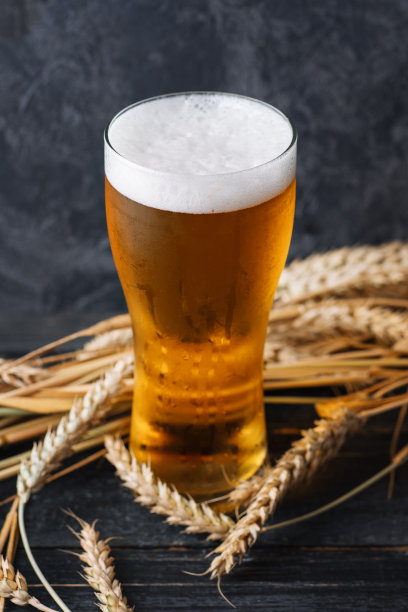 一杯淡泡沫啤酒，放在一张有麦穗的深色木桌上图片下载