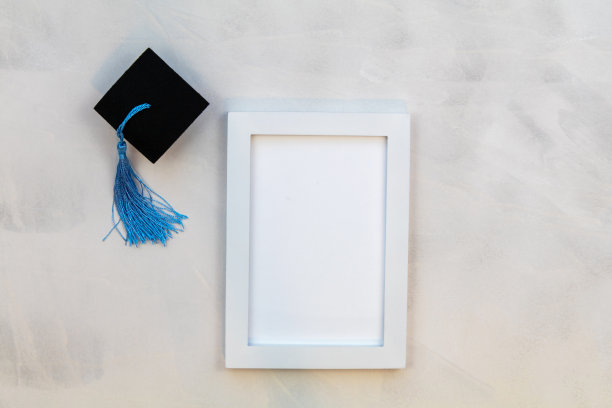 白色框架模型与毕业帽和蓝色流苏在灰色水洗背景平铺复制空间图片下载