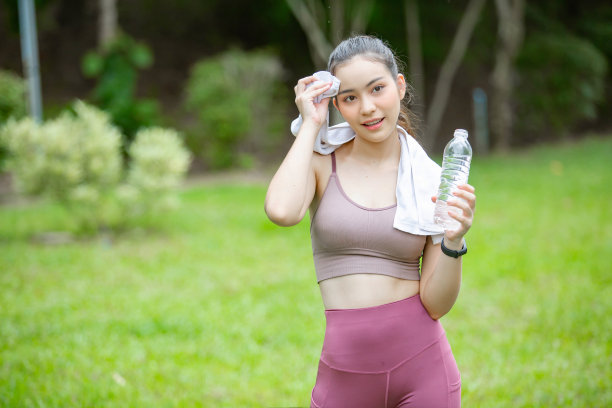 漂亮的女人穿着运动服，在绿色的草坪上有普通的水图片下载