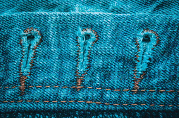 衣服项目蓝色石磨褪色牛仔裤棉织物纹理接缝，扣，纽扣和铆钉，宏观，特写图片下载