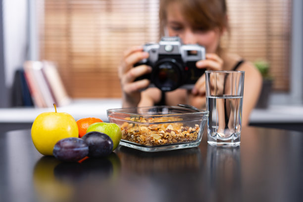 模糊照片的一个女孩正在拍摄她的健康早餐。什锦麦片，水和水果。完美的健康的早餐。图片下载