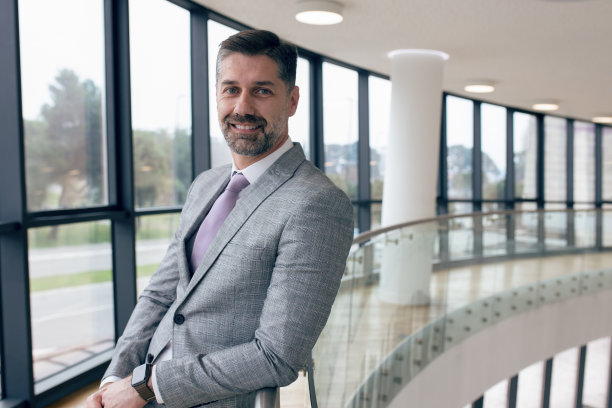 成功的中年商人在他的公司窗户附近摆姿势。图片下载