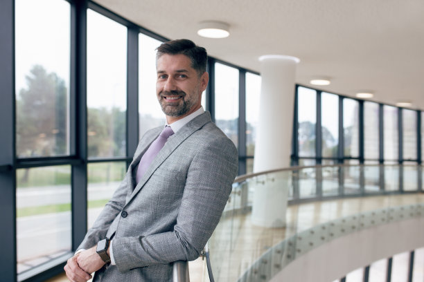 成功的中年商人在他的公司窗户附近摆姿势。图片下载