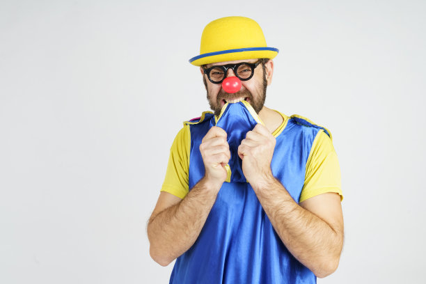 一个穿着亮蓝黄相间西装的小丑吓得咬住了领带图片下载