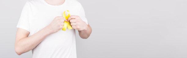 青年男子在白色t恤举黄色丝带意识象征自杀，肉瘤骨癌，膀胱癌，肝癌和儿童癌症的概念。卫生保健。Copyspace。图片下载