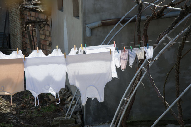 白天在室外晾晒衣物，在后院用绳子吊着防冠状病毒的口罩，城市背景图片下载