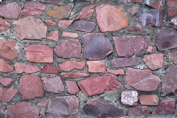 墙壁上的大块花岗岩原石颜色为红色，背景花岗岩不均匀的云雾起来图片下载