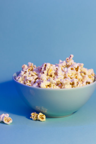 爆米花的明亮图片。蓝色盘子里的爆米花。蓝色背景。平铺，拷贝空间。横幅图片下载