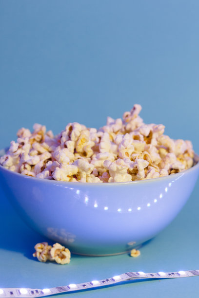 爆米花的明亮图片。蓝色盘子里的爆米花。蓝色背景。平铺，拷贝空间。横幅图片下载