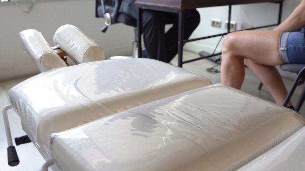 白色的担架在办公室，女病人坐在骨科医生前面图片下载