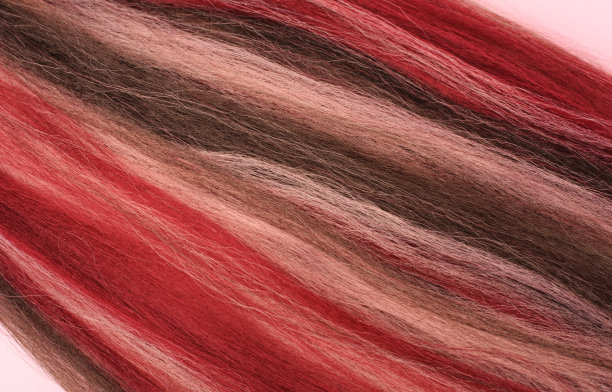 明亮的合成头发编织不同的发型，辫子，脏辫，非洲式辫子。粉色和红色的Kanekalon图片下载