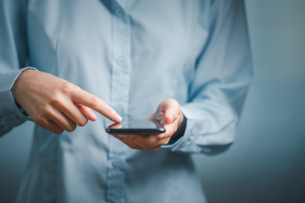 近看，女人的手在用黑色的智能手机。图片下载