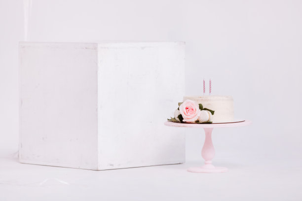 美丽的白色奶油蛋糕装饰2年蜡烛和玫瑰在白色工作室。生日聚会-概念的一年的出生，聚会，庆祝生命和难忘的时刻。图片下载